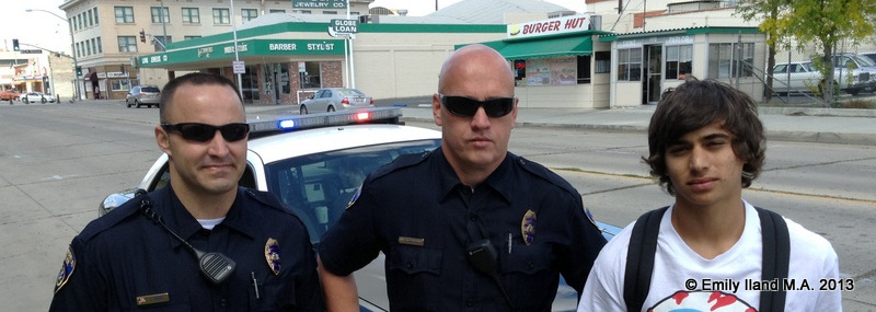 Two police officers standing with a young skateboarder